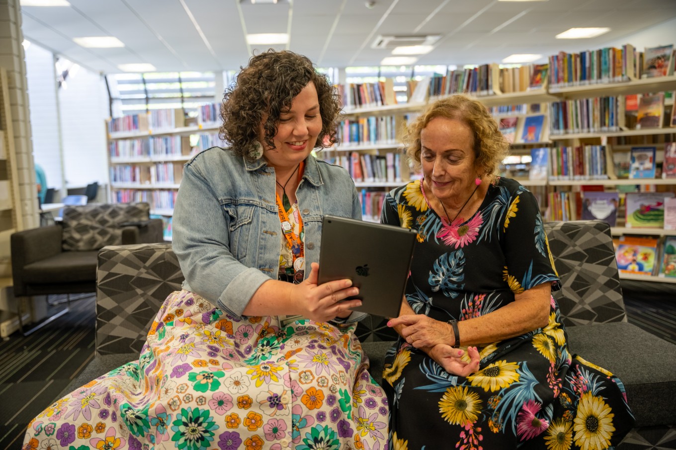 A librarian helping a person with their computer troubles at a local library.