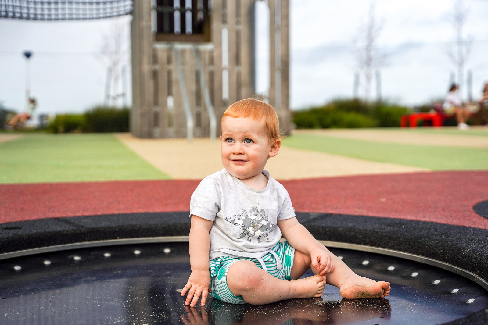 A kid sitting on a trampoline in the Playground.