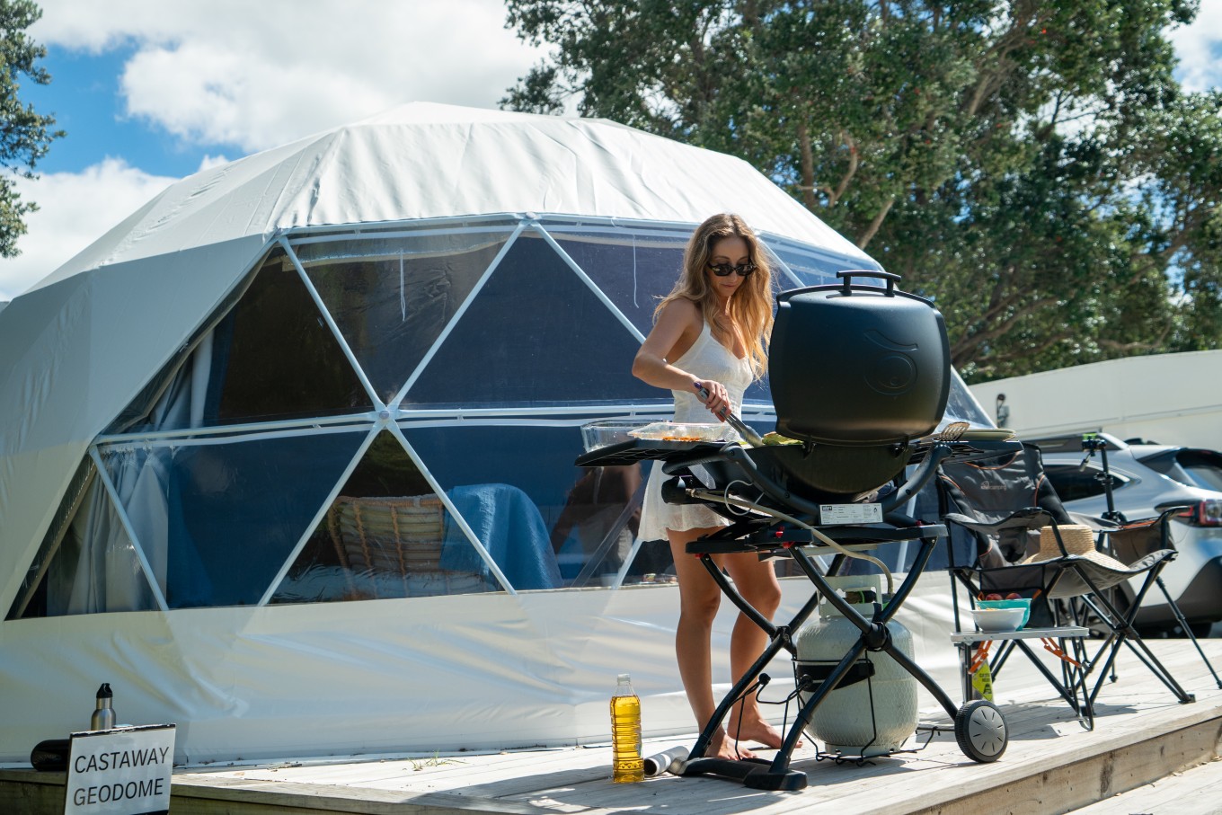 A lady having a bbq in front of a geo dome.