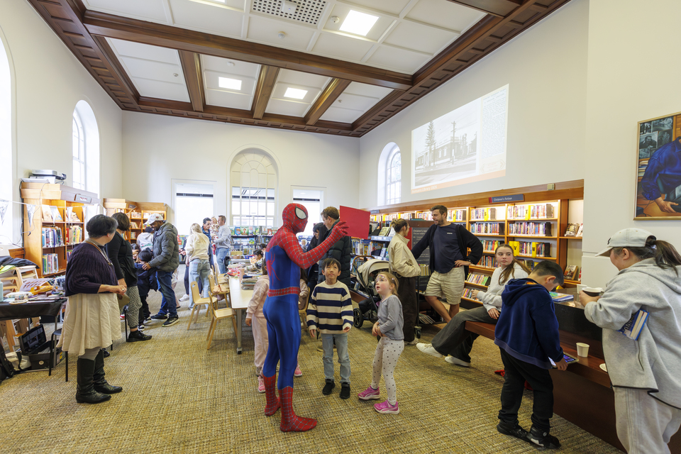 A group of people at a local library with Spider Man in attendance.