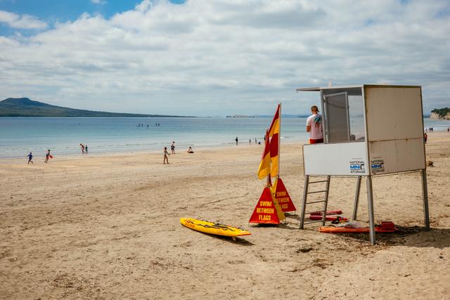 Surf lifesaving tower at Takapuna Beach with kids playing on the sand