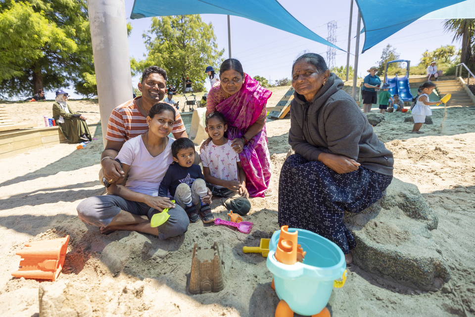 A family enjoying playing in the sandpit at a local park on a sunny day. 