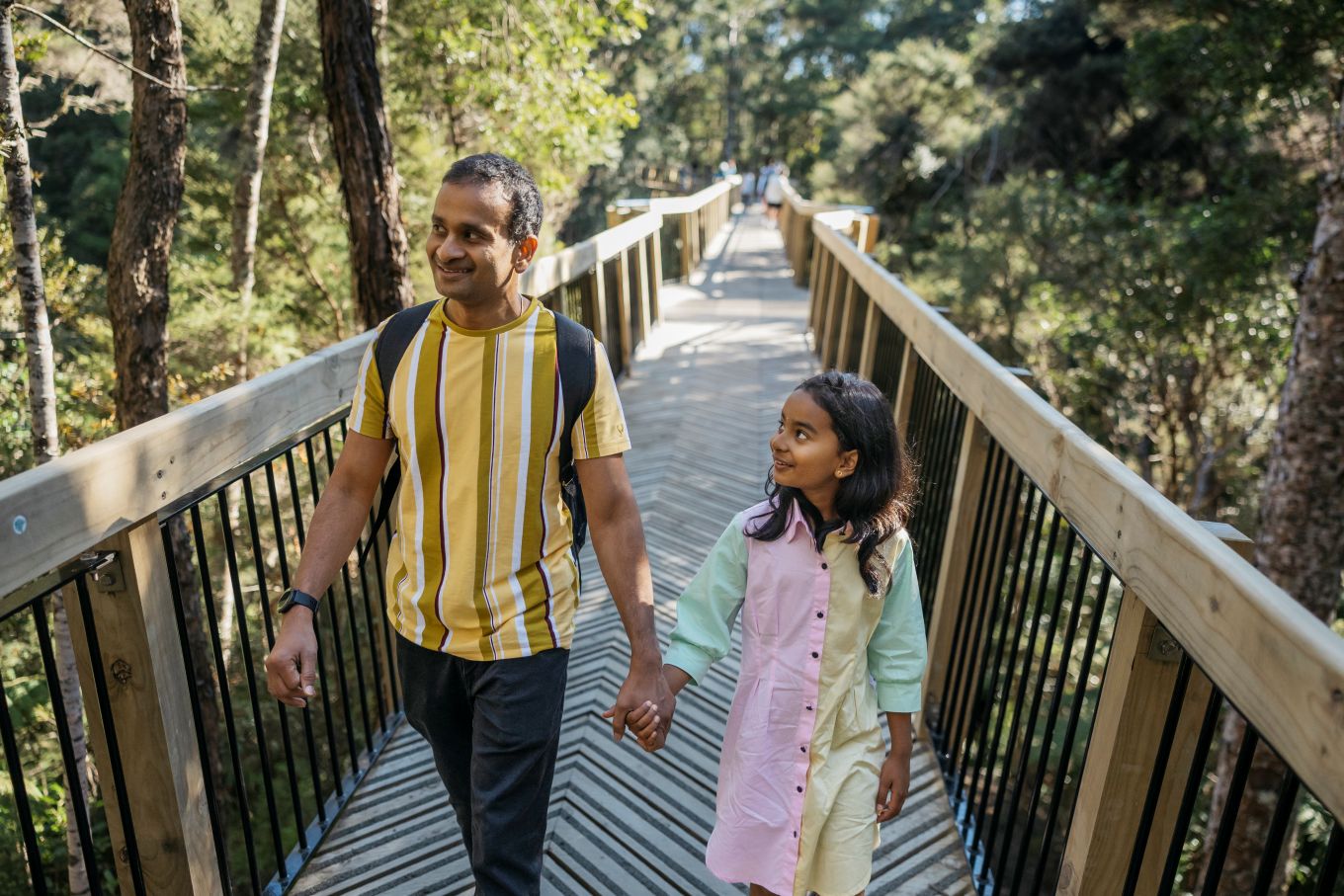 A man and a girl walking across a bridge.