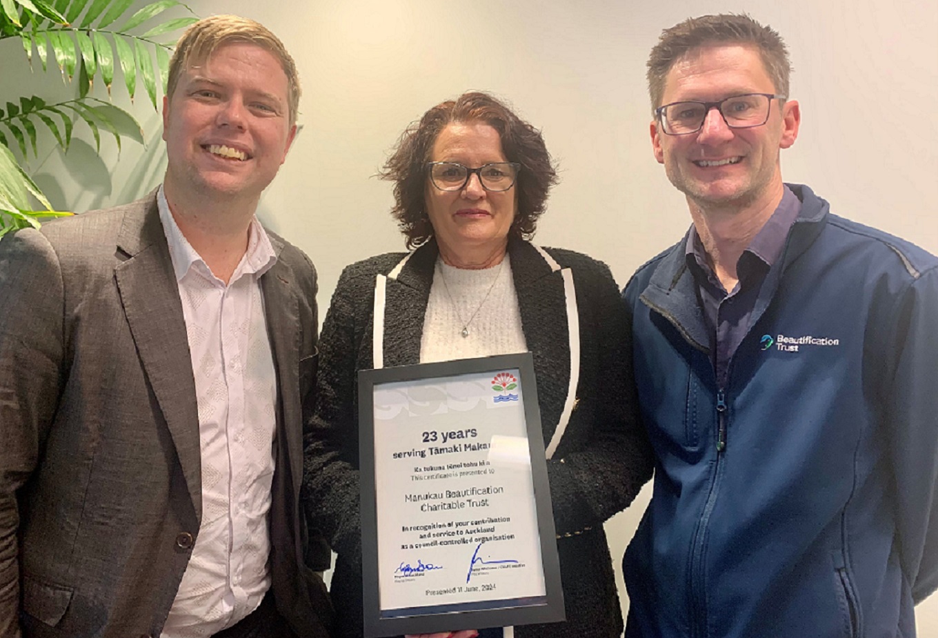Auckland Council's CCO Direction and Oversight Committtee chair Cr Shane Henderson with Beautification Trust chair Audrey Williams and chief executive Daniel Barthow and a certificate recognising 23 years of service.