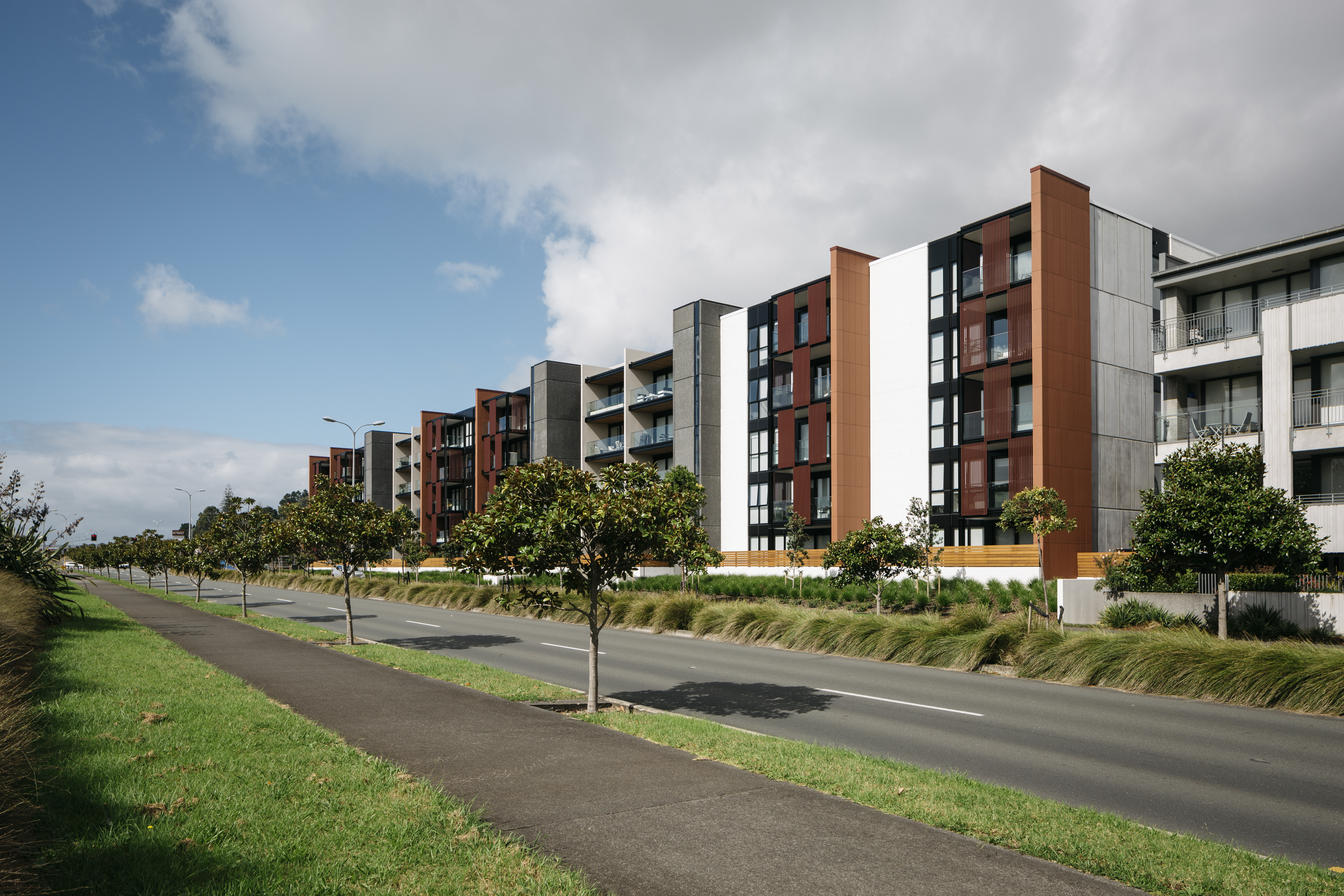 Picture shows a row of apartments on a street on a sunny day. Apartments are one of the housing choices residents of Auckland have.