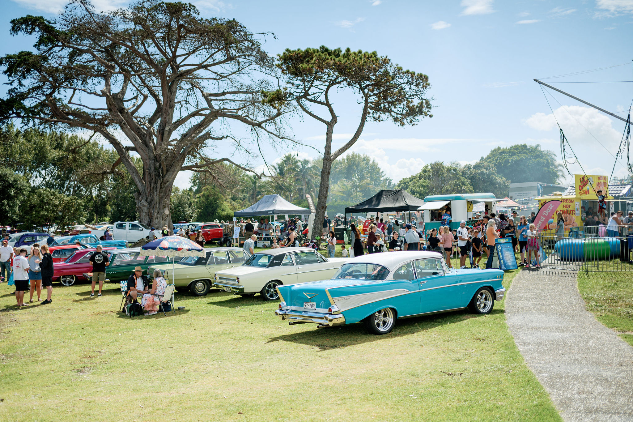 Classic cars parked up at iconic community day event with lots of stalls and eventgoers in the background