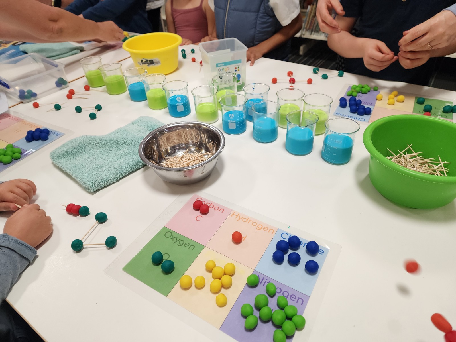 Hands-on chemistry basics with colourful liquid filled beakers and pretend clay atoms