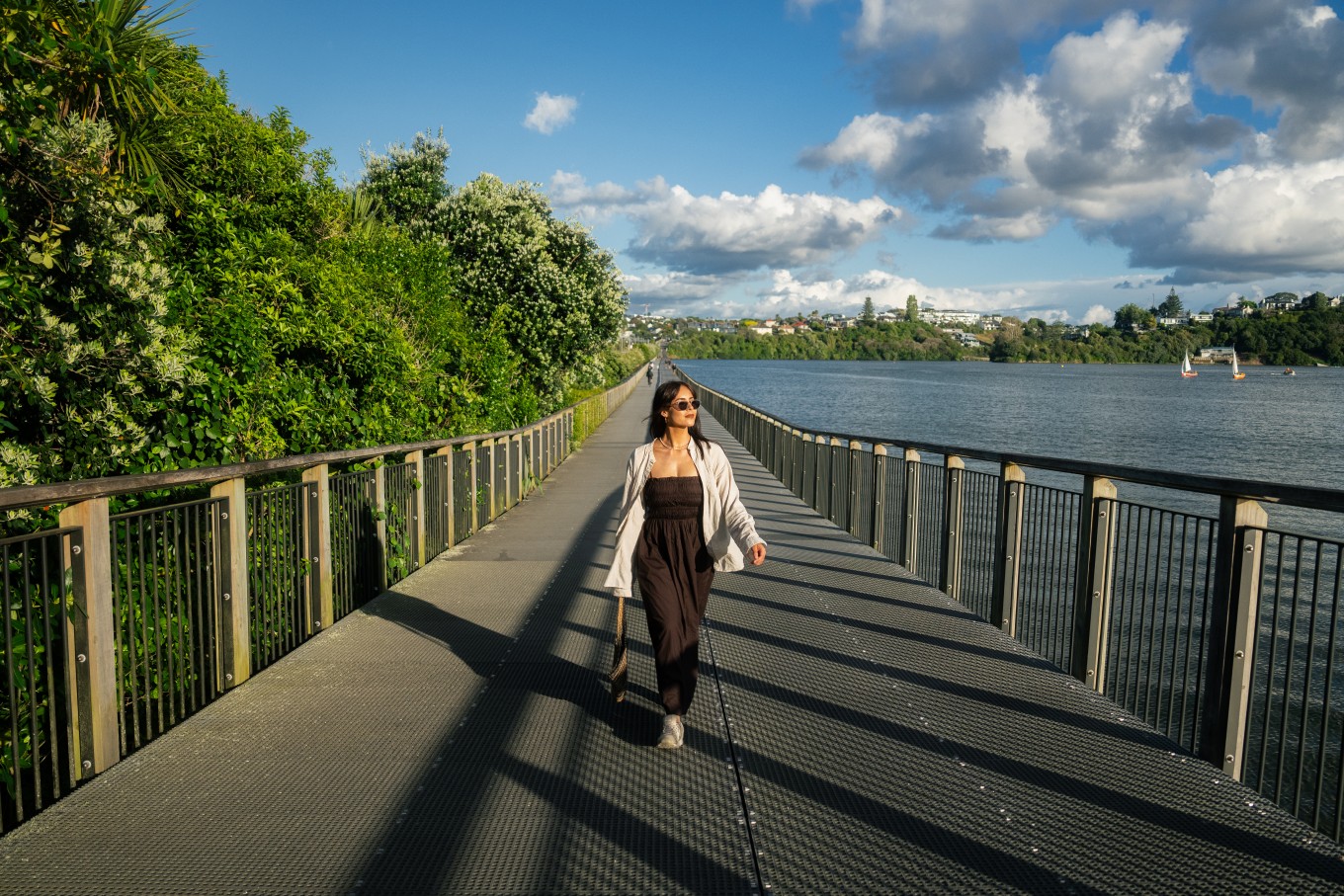 A lady walking on a walkway above a lake.