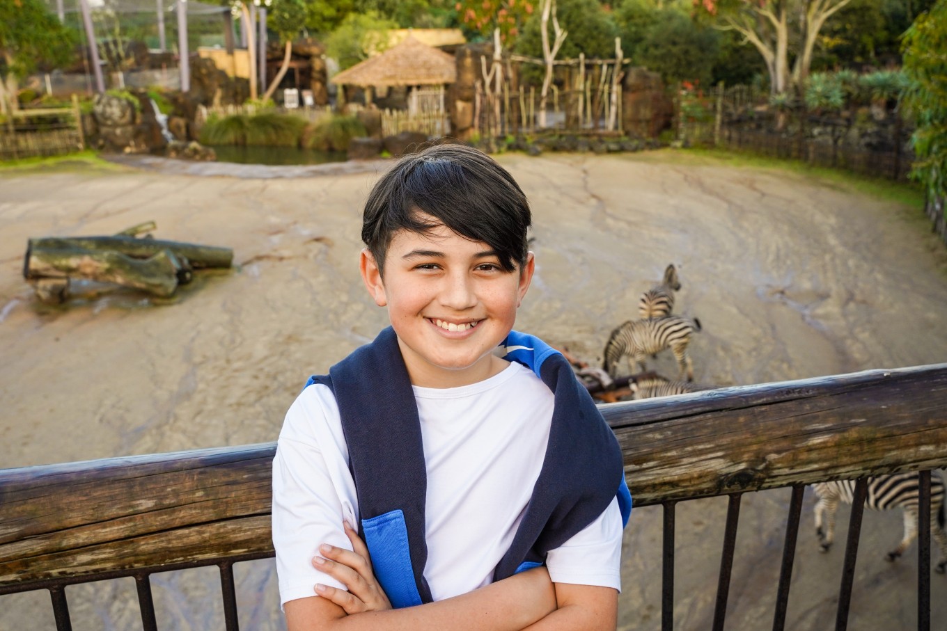 A young man enjoying the zebra enclosure at Auckland Zoo.  