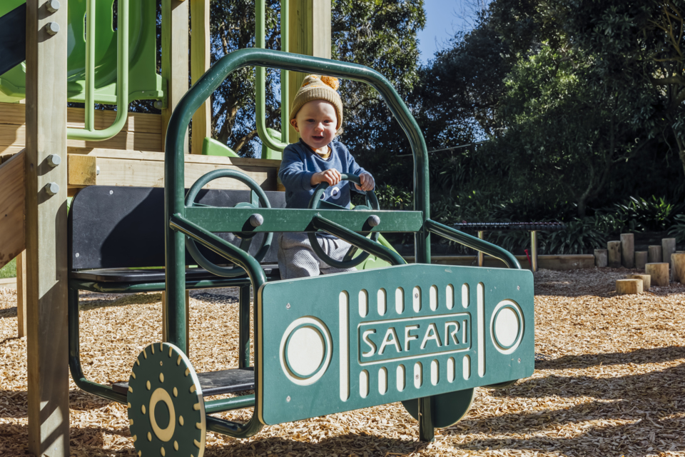 Small person behind playground steering wheel.