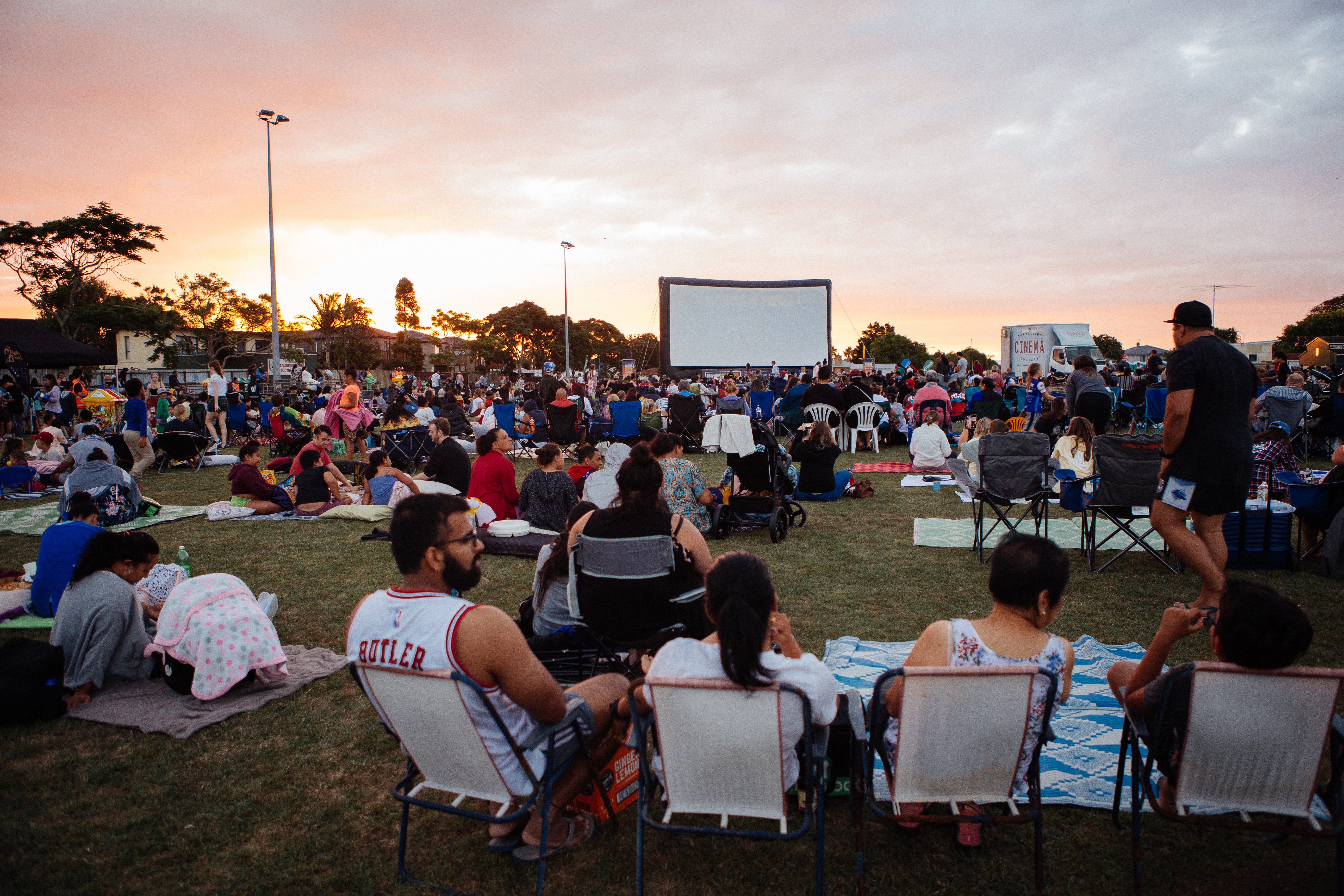 The community of Papatoetoe gather together on picnic blankets and camp chairs to watch a 'Movies in Parks' movie at Kingswood Road Reserve as the sun sets