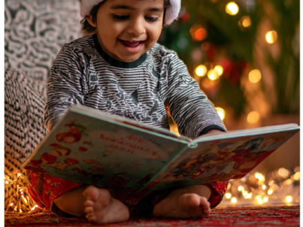 Indian toddler in santa hat reading a book OA_5idgizgd.png