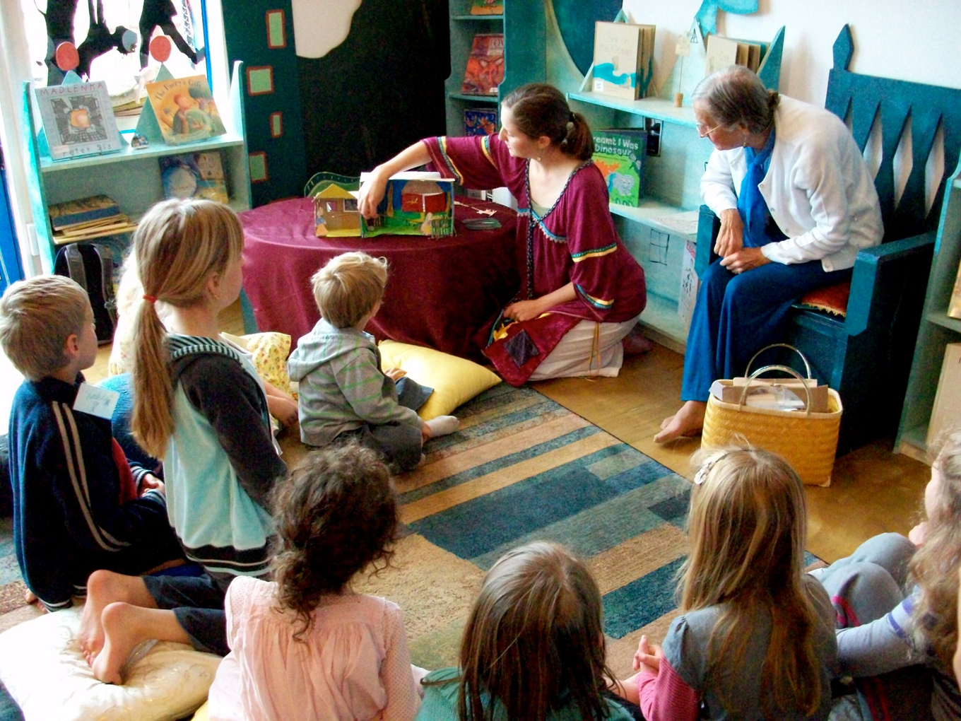 A community storytelling session with adults and children in a room together. 