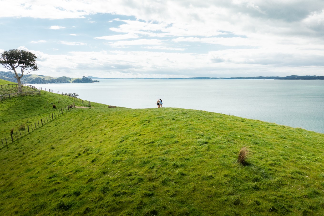 Two people walking along the coastline at Duder Regional Park. 