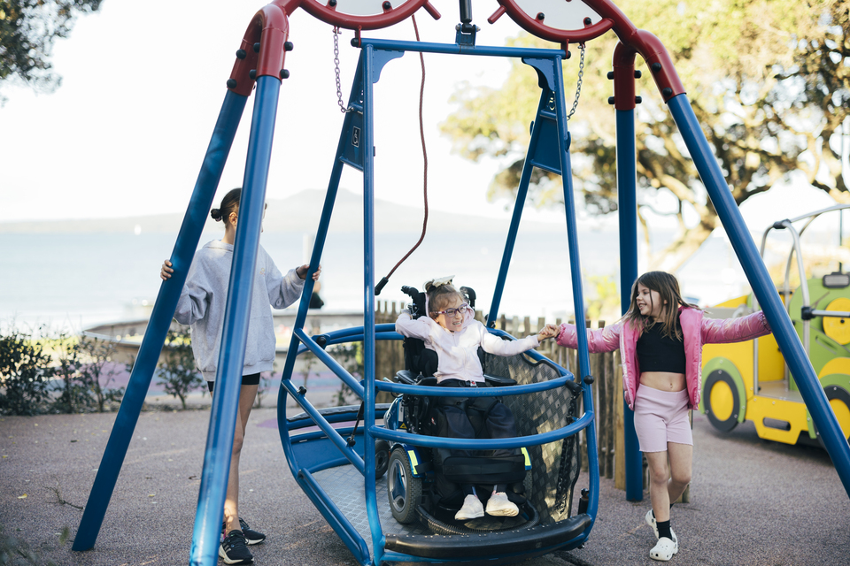 A girl in a wheelchair riding in a accessible swing. 