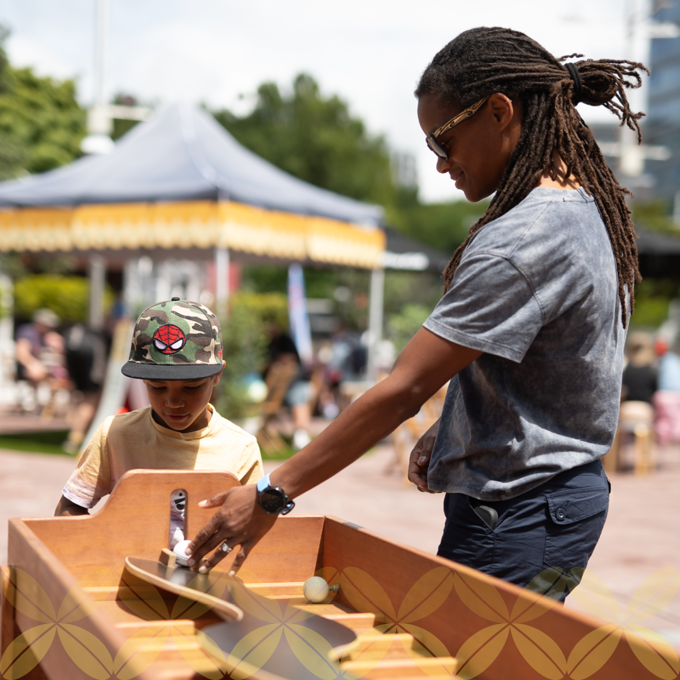 A man showing a child how to play with a ball in a wooden table