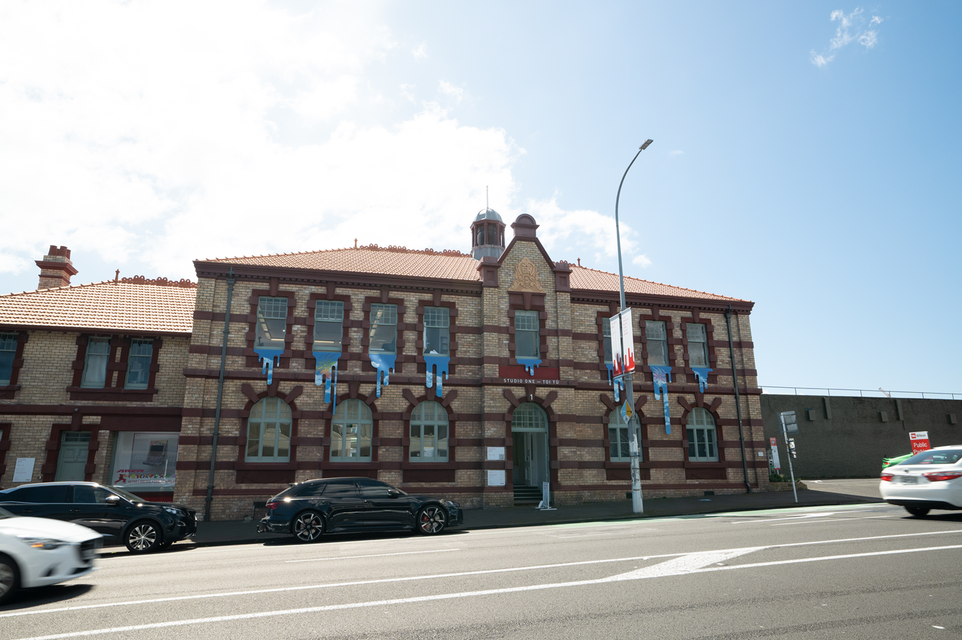 A brick building on the side of a busy road. 