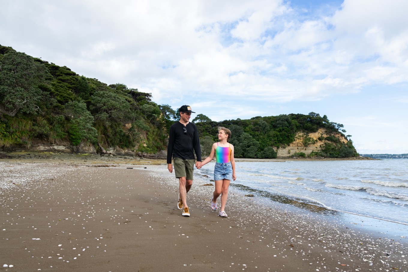 An adult and child in the foreground in Kendall Bay, with the beach stretching out in the background