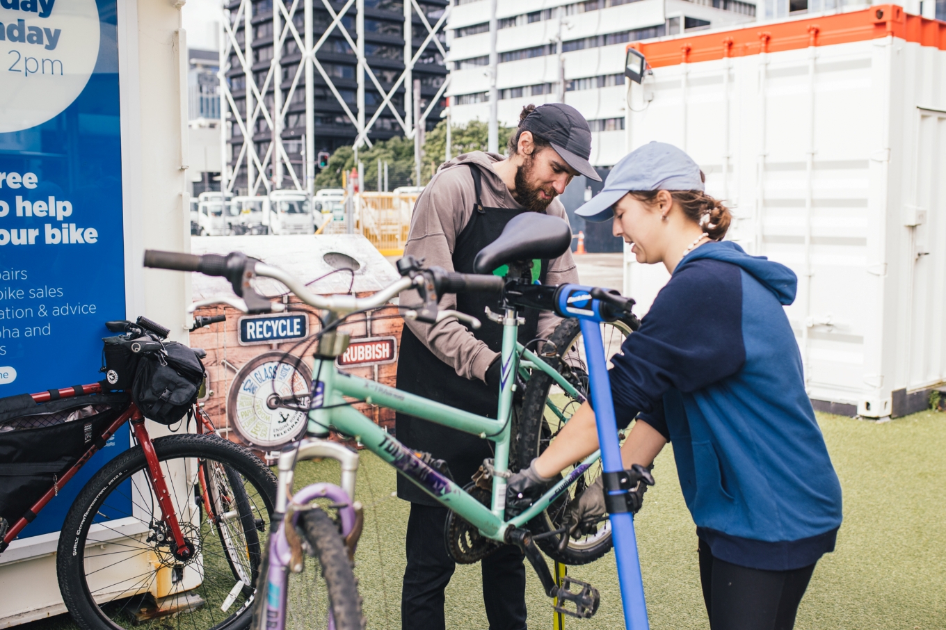 Two people working on a bike with tools.