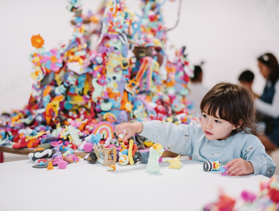 A child sitting next to a pile of toys. 