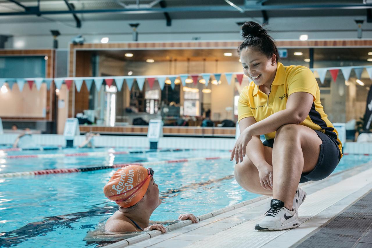 A lifeguard on hand to help out with a person in a pool. 