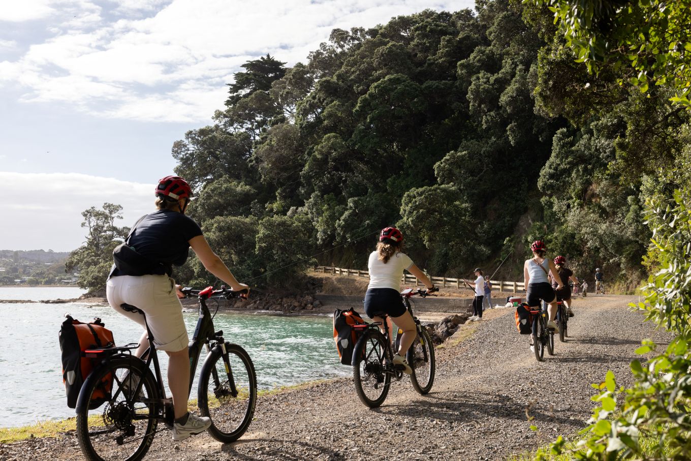 A group of cyclists riding in formation by the water. 