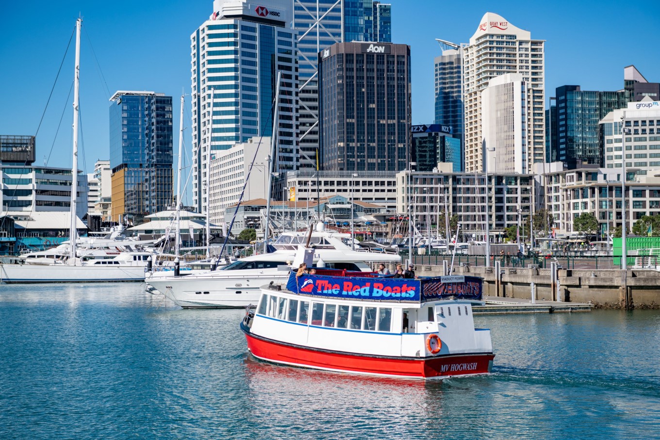 Red Boats ferry sailing past city waterfront.