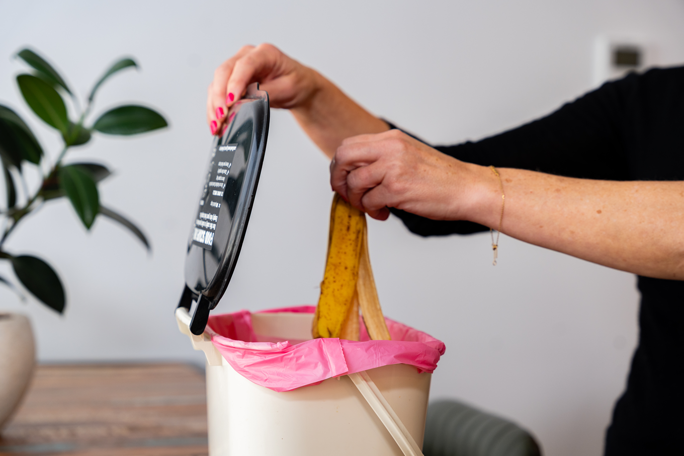 A person putting a banana in a food scraps bin. 
