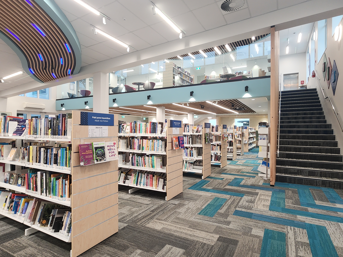 A two level library interior with shelves fulled with books. 