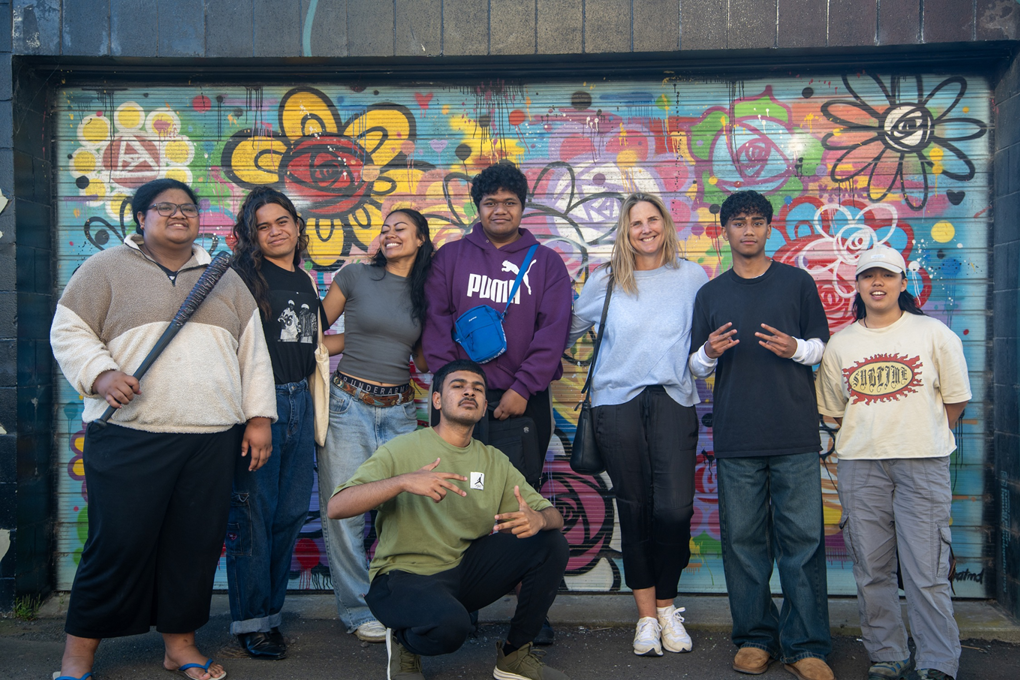 Rangatahi / youth in a group photo in front of a graffiti wall