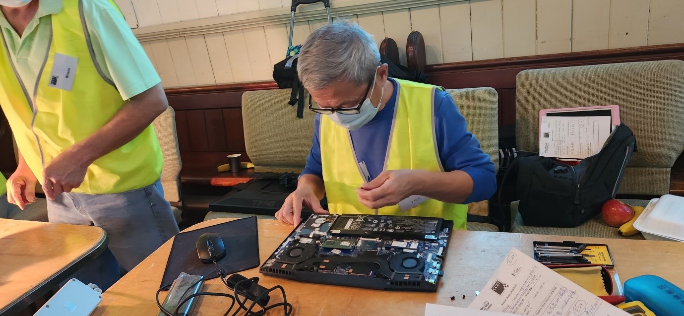 Volunteer elbows deep in electronics repair at Epsom Repair Cafe April 2023