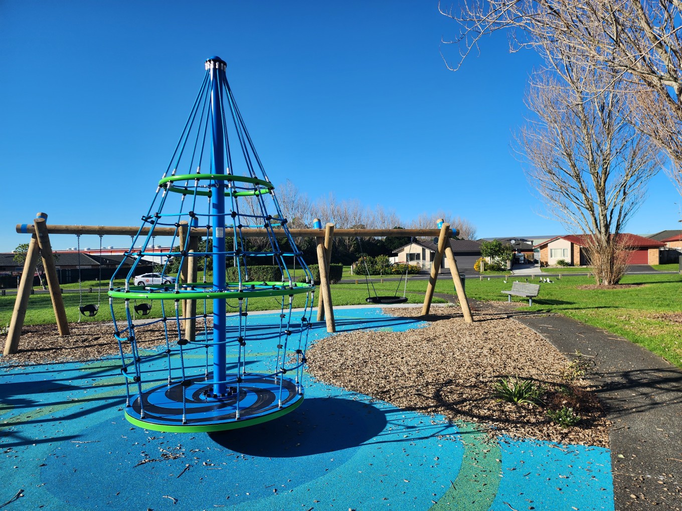 A merry go round and swing set at a local playground. 