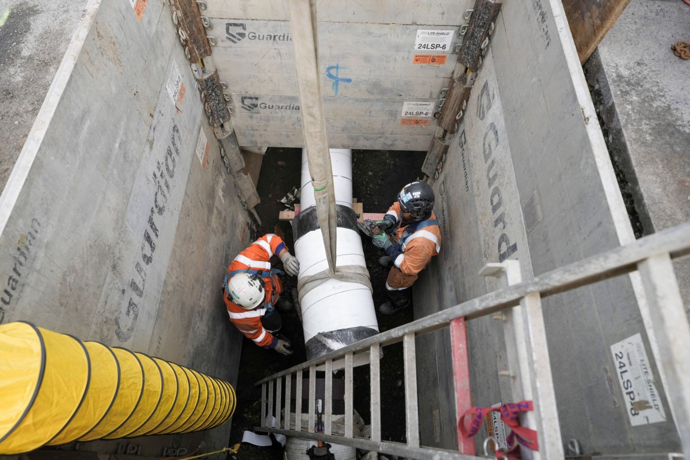 Construction workers installing a pipe underground. 