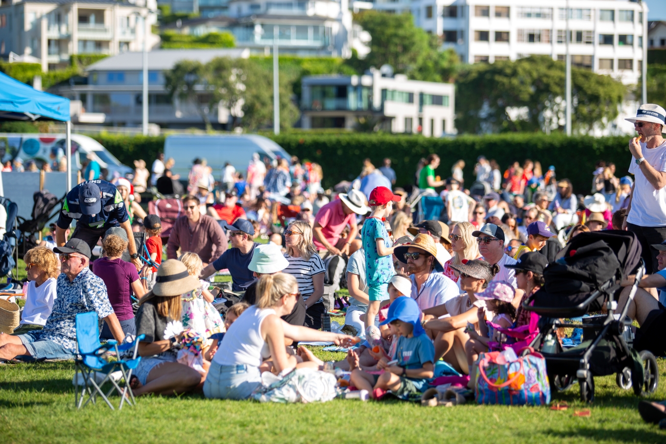 Lots of families having picnics together on a sunny day in a park.