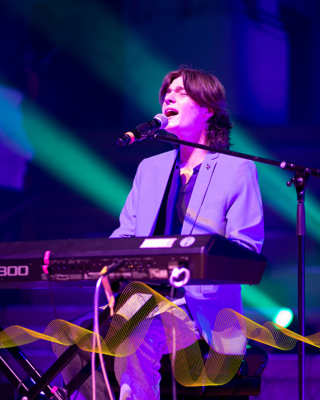 A guy on stage playing a keyboard.