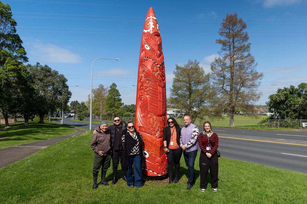Local iwi representatives next to a Māori carving. 