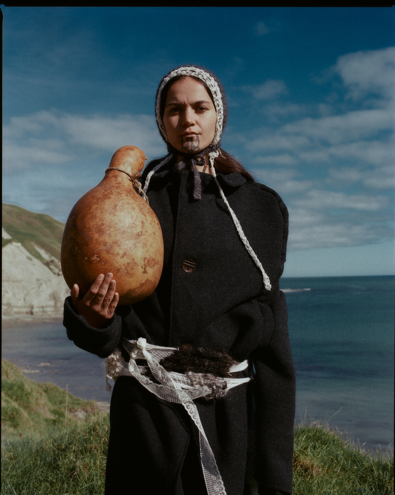 A Māori centric fashion outfit on a Māori women with a Tā moko on her chin. 