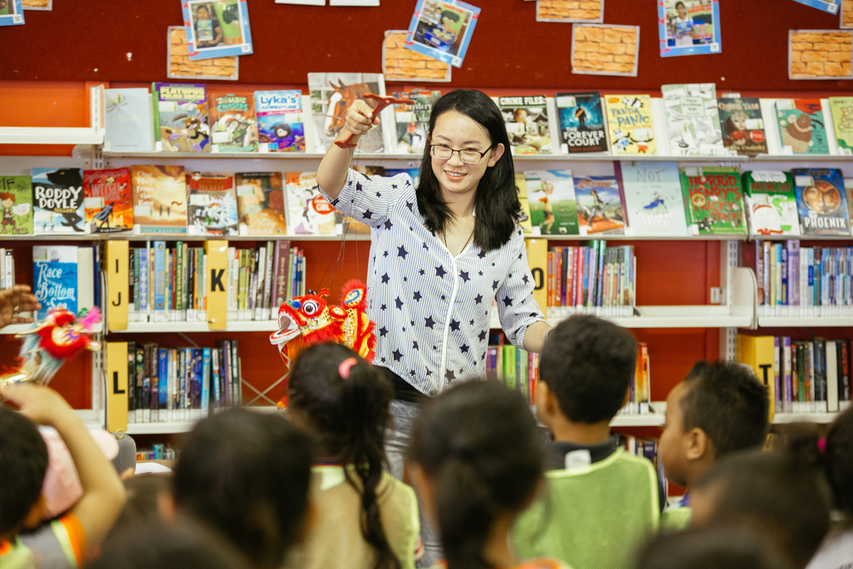 A lady performing a traditional Chinese dragon puppet show for kids at a local library. 