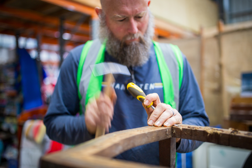 A man using tools to repair an item of furniture.