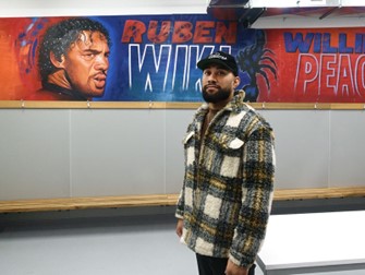 A local artist stands in front of one of a series of new murals he painted for Otara Scorpions in 2022