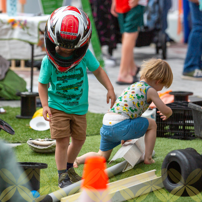 A child with a motorcycle helmet playing with another child