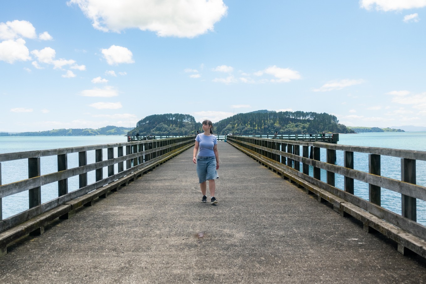A lady walking down a boardwalk.