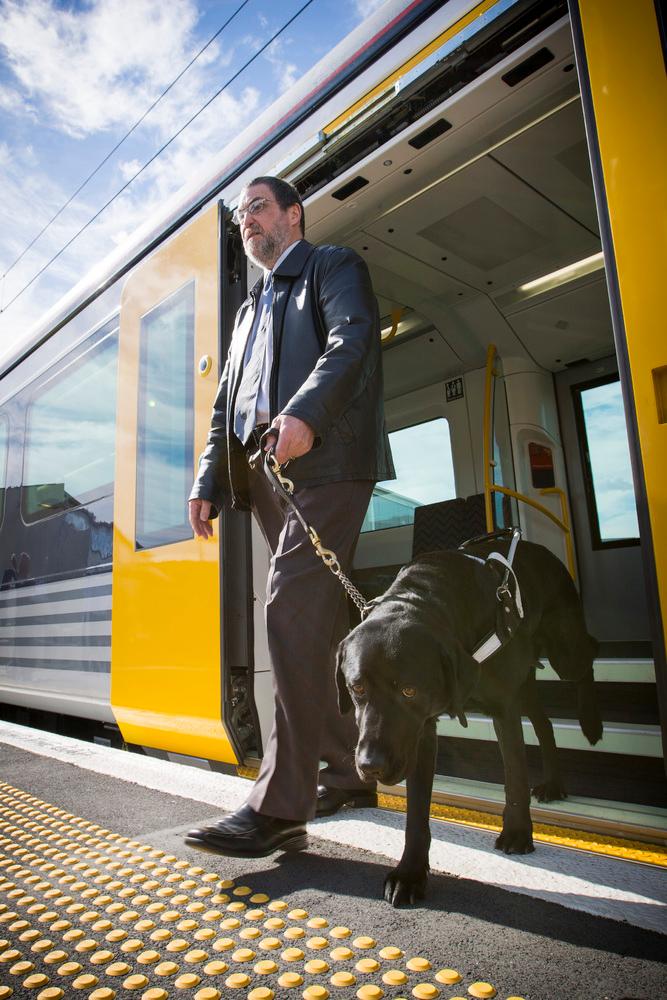 Chris Orr with his dedicated working dog Noble, exiting one of Auckland’s accessible and carbon-free electric trains.