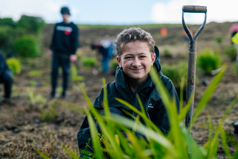 A child composting in front of a shovel. 