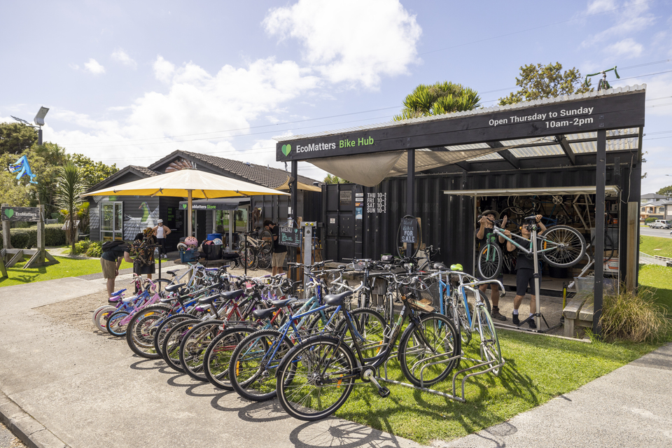 A rack of bikes placed outside a bike hub on a sunny day. 