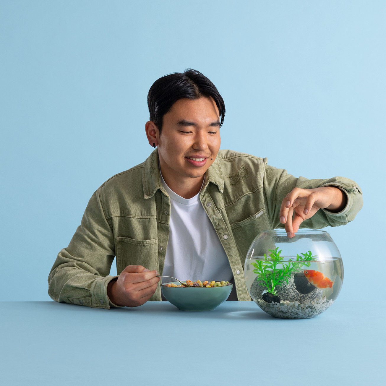 Man feeding a goldfish in a bowl