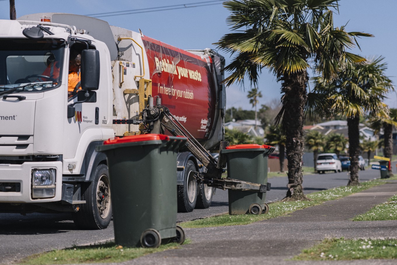 Auckland Council rubbish truck picking up rubbish bins with a mechanical arm