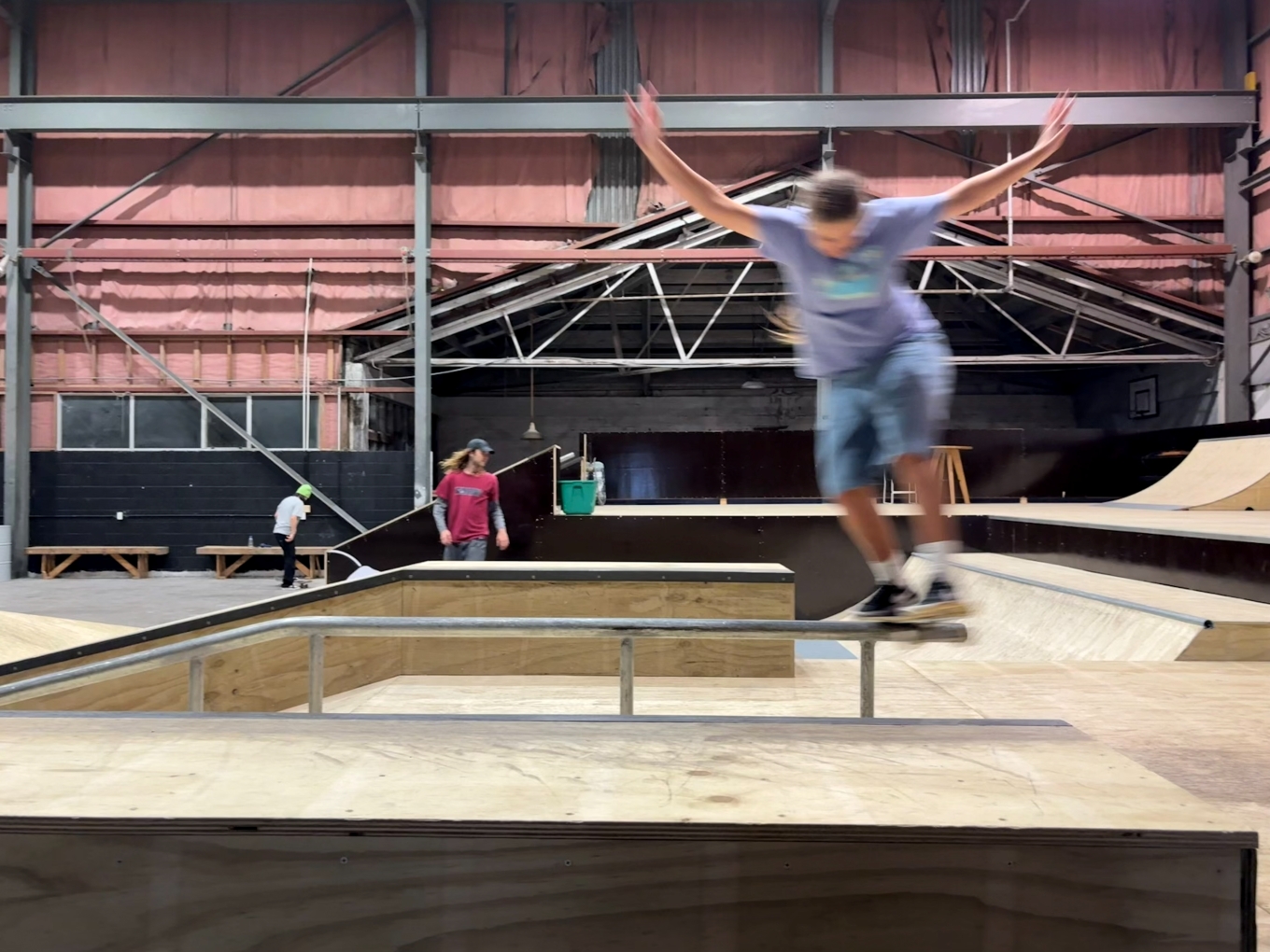 Someone blurred with speed doing a skateboard trick in a skate park.